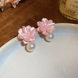 Macro shot of 3D pink resin flower earrings with white pearl pendants on ceramic plate
