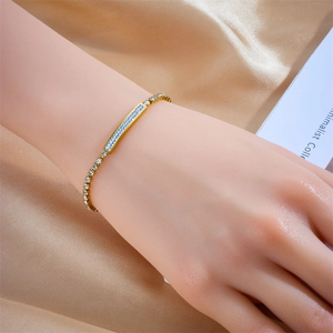 Detail eines vergoldeten Titan-Armbands mit Pavé-Strass auf seidigem Hintergrund