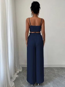 Vista posteriore di un elegante completo blu navy a due pezzi con top a bretelle e pantaloni larghi