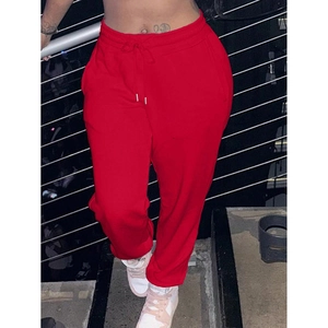 Detail view of red athletic sweatpants featuring an adjustable drawstring and ribbed cuffs