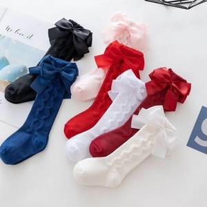 Detail of knit knee-high socks with large satin double bows and cable patterns