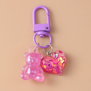 Detail of pink resin bear and glitter heart charm on a purple metal keychain clip
