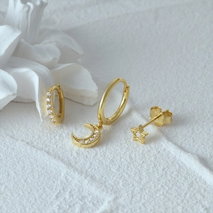 Macro shot of gold S925 silver earrings set with moon, star, and rhinestone details
