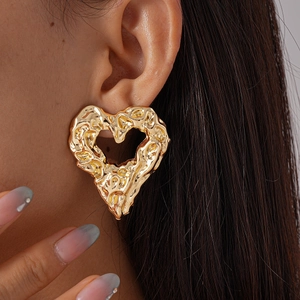 Macro view of gold hammered heart earrings featuring unique liquid metal textured surface