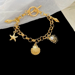 Macro shot of gold stainless steel bracelet with starfish shell pendants and OT toggle clasp