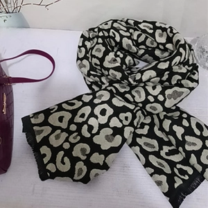 Thick leopard print scarf in black and grey with short tassels on a white surface