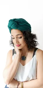 Detail of emerald green pleated knit turban cap showing elegant vintage fabric texture