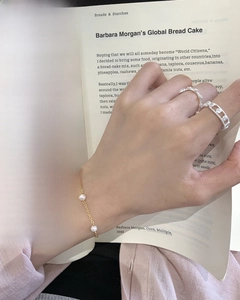 Elegant s925 silver beaded bracelet and sparkling rings worn while reading a book