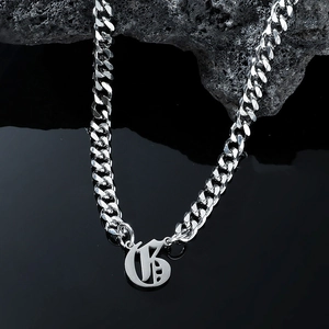 Close-up of silver Cuban link necklace with Gothic B pendant on volcanic rock
