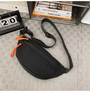 Waterproof black nylon chest bag with orange zipper pullers placed on a checkered floor