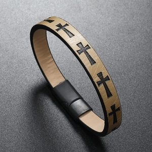 Detail of beige leather bracelet featuring black cross patterns and magnetic buckle