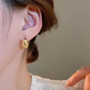 Close-up of elegant 18K gold plated teardrop earring worn by a model with mirror finish