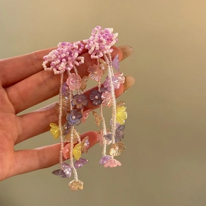 Macro view of colorful beaded flower tassel earrings featuring translucent resin petals