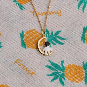 Gold moon astronaut necklace with micro-pave cubic zirconia on a fabric background