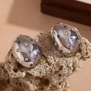 Macro detail of silver pebble earrings with colorful zircon stones on coral rock