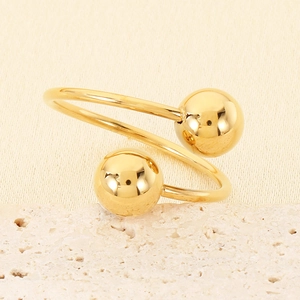 Detailed view of golden double-ball open ring on a natural stone surface
