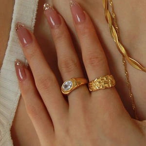 Detail of gold lava textured band and oval zircon ring on a model's hand