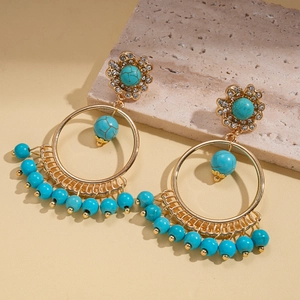 Detail of bohemian gold hoop earrings with turquoise beads and rhinestones on stone