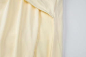 Close-up of pale yellow knitted fabric texture and elastic fibers of backless mini dress