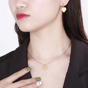 Elegant gold heart pendant necklace and stud earrings set worn by a fashion model