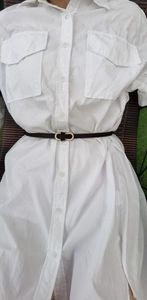 Detail of a thin black leather belt with golden double ring buckle on a white shirt
