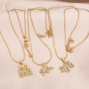 Gold plated MAMA and Mom letter necklaces with cubic zirconia on satin background
