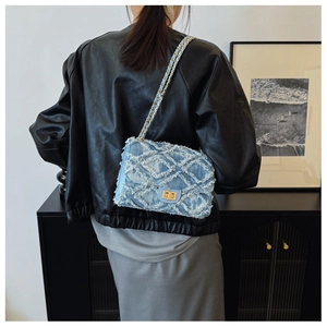 Macro detail of denim flap bag with frayed lattice pattern and gold twist lock