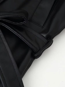 Gros plan sur les coutures d'une ceinture en similicuir noir avec détail de boucle