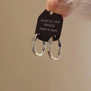 Detail of twisted 925 silver hoop earring with polished metallic surface and mirror finish