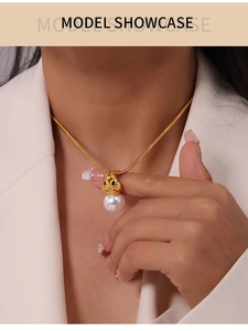 Close-up of golden squirrel pearl pendant on snake chain necklace worn by a model