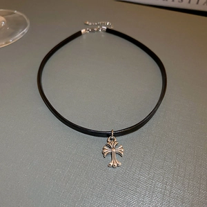 Detail of silver cross pendant on black leather cord with adjustable lobster clasp