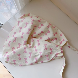 Vue détaillée du tissu en coton crème avec motifs de nœuds roses et pois bleus