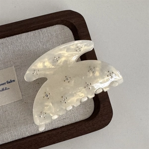 Detailed close-up of cream acetate hair claw clip with embedded sparkling rhinestones
