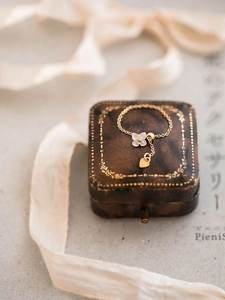 Detail of adjustable gold chain ring with white shell flower and heart pendant