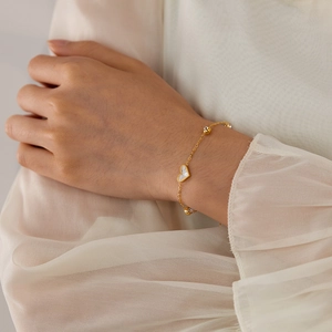 Close-up of elegant gold heart bracelet with white shell inlay and beads on wrist