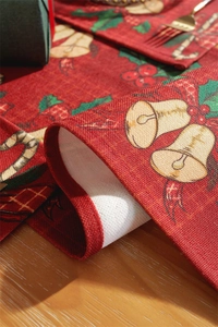 Close-up of festive Christmas table runner with bells and candy canes on wood