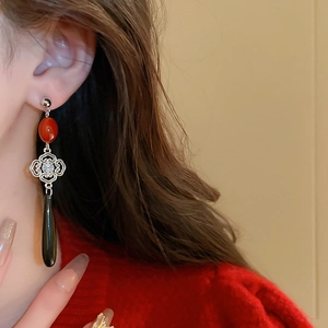 Detailed view of Chinese knot earring with red bead and black teardrop pendant
