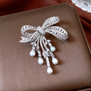 Macro shot of bow brooch with zircon inlay and five pearls on luxury jewelry box