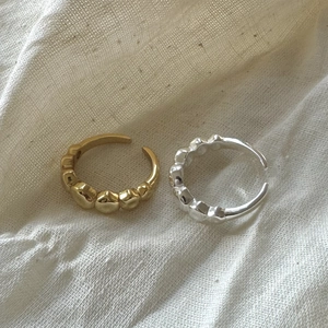 Detailed view of gold and silver irregular heart wavy rings on textured beige fabric