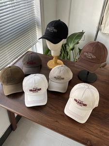 Detail of embroidered lettering on cotton baseball caps with reinforced stitching on the brim
