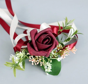 Vue macro d'une boutonnière de rose artificielle rouge foncé avec rubans de soie et feuilles