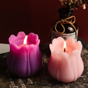 Dettaglio di candele profumate a forma di tulipano accese in tonalità viola e rosa