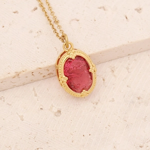 Retro gold stainless steel necklace with oval red natural stone pendant on stone background