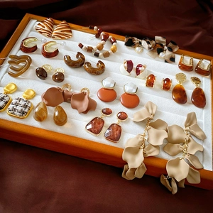 Flat lay of vintage style amber and floral earrings displayed on white velvet tray