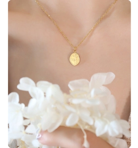 Detail of elegant gold leaf pendant necklace worn on neck with soft floral accents