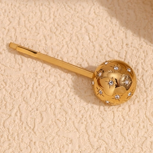 Makro-Detail einer 18K gold kugelförmigen Haarspange mit funkelnden Strass-Sternen