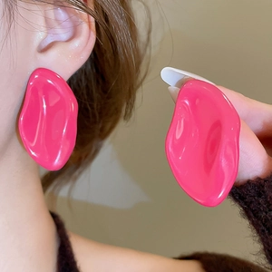 Dettaglio di grandi orecchini irregolari in smalto rosso rosa indossati da una modella