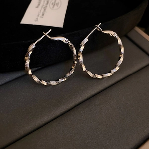 Macro detail of silver-toned twisted textured hoop earrings on a black velvet display
