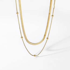 Double-layered gold flat snake chain necklace with round bead accents on white background