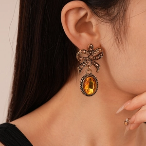 Close-up of vintage gold bow earrings with amber stones on a model for styling
